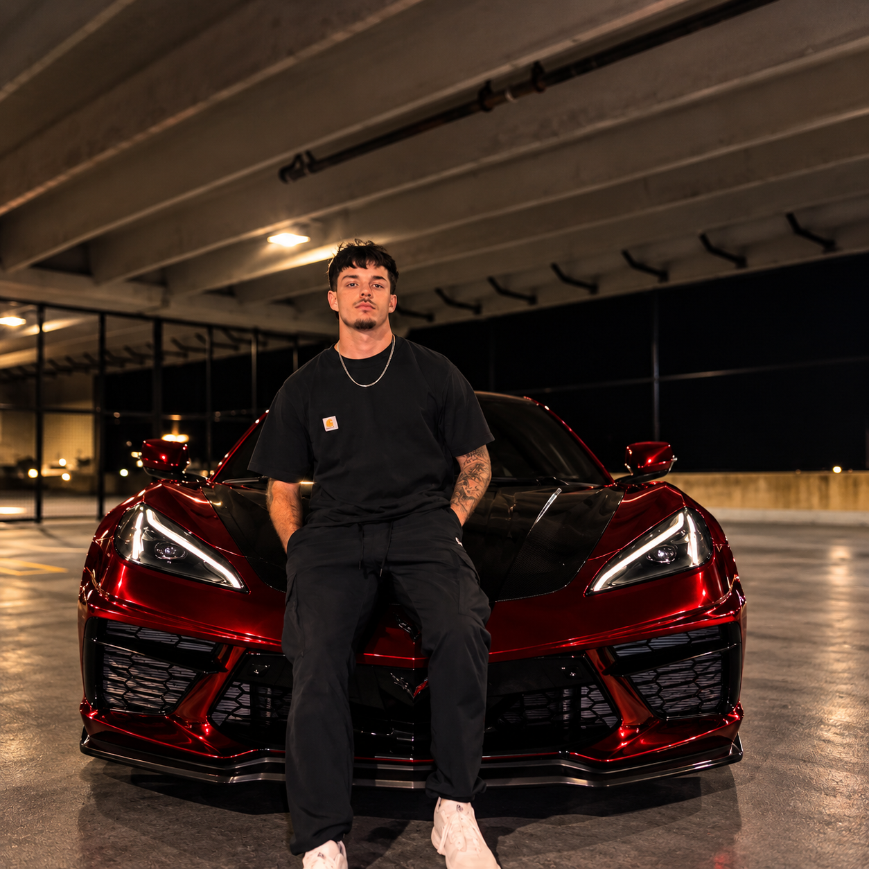 Cole Musser, owner and lead installer at 918Wraps, sitting on a red wrapped Corvette