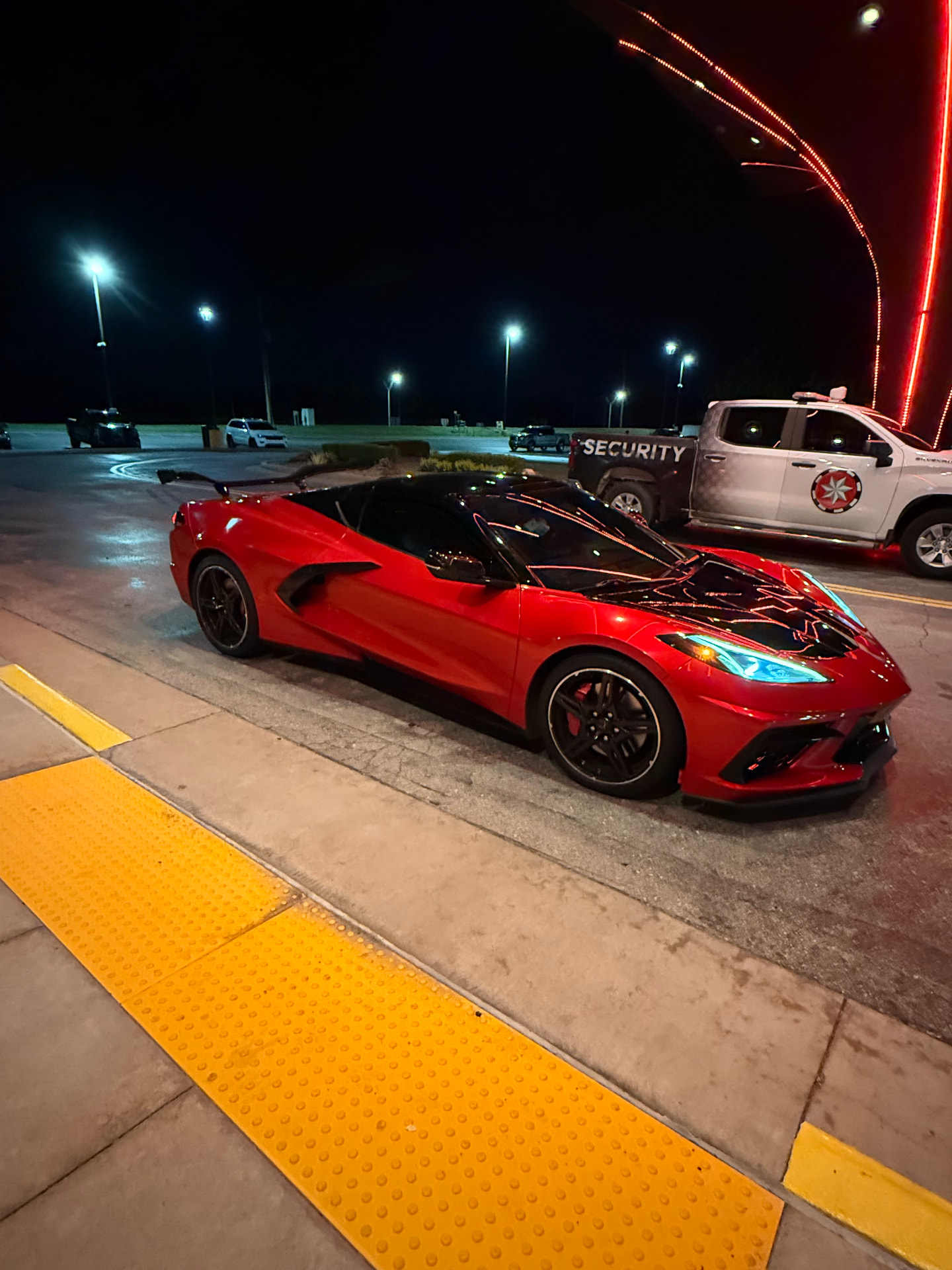 Red Corvette with carbon accents under the lights at night